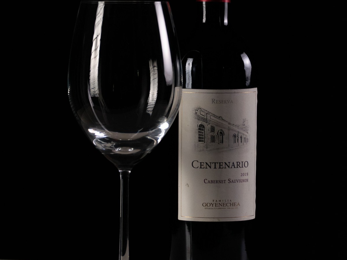 Botella de vino tinto junto a una copa